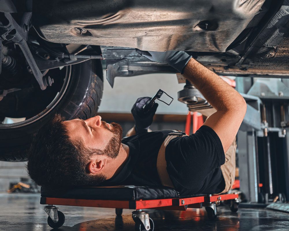 A mechanic inspecting a vehicle in a well-lit garage.